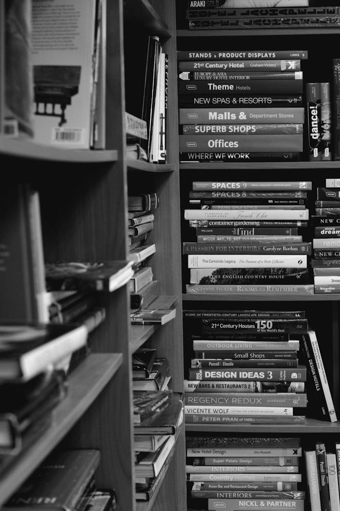 our-story An organized bookshelf stacked with various books in a monochrome setting, illustrating a love for literature.